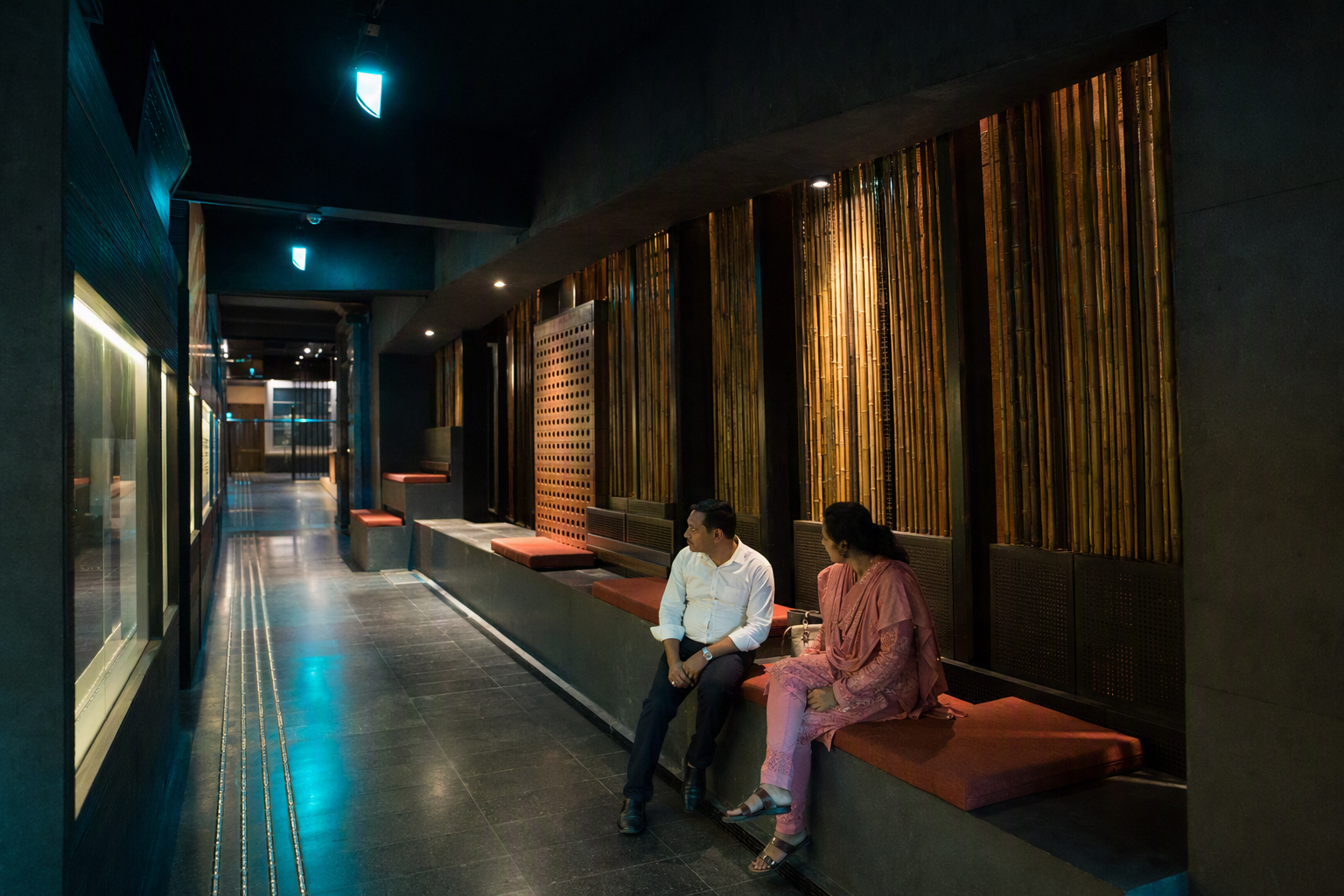 A quiet seating cove with backed chairs, armrests, wheelchair spaces, and soft indirect lighting