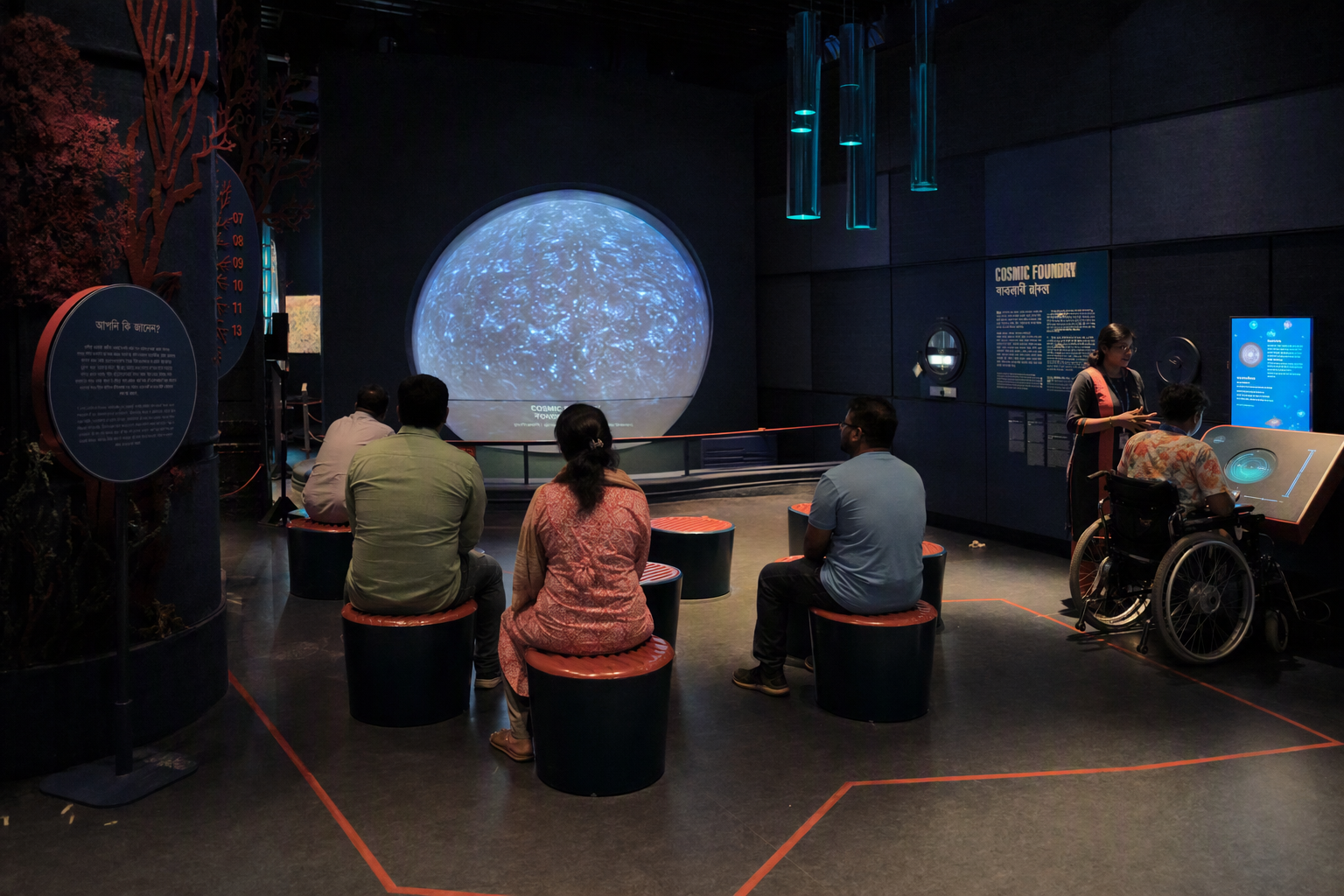 A wheelchair user and companion exploring a softly lit Cosmic Foundry chamber with clear floor space and portable seating
