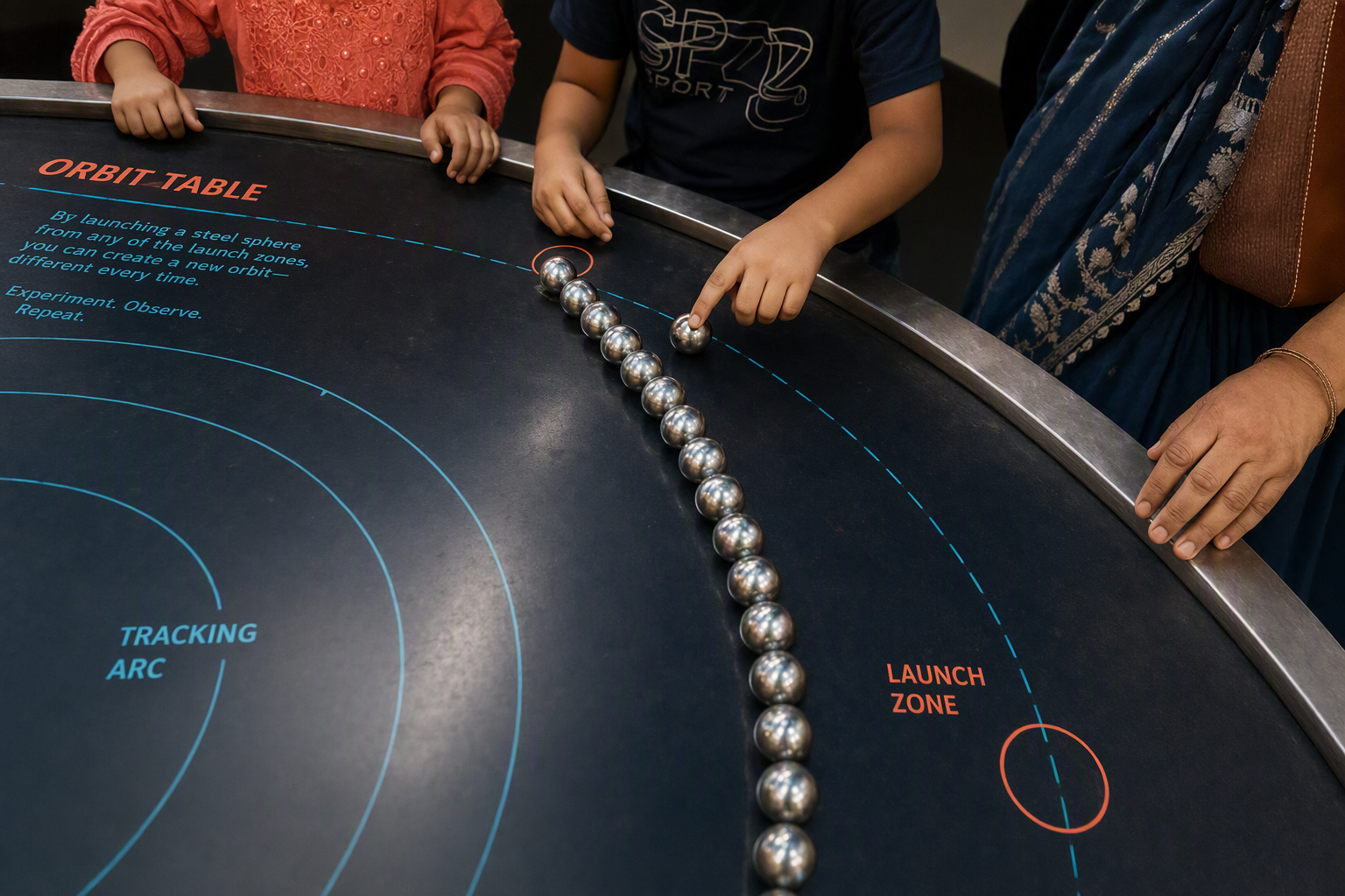 Glowing spheres tracing curved paths around the hands-on Orbit Table