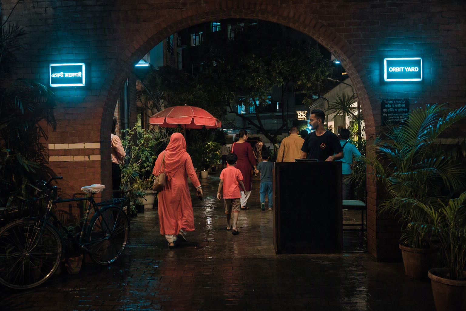Visitors walk beneath a glowing cyan canopy into Orbit Yard at early evening
