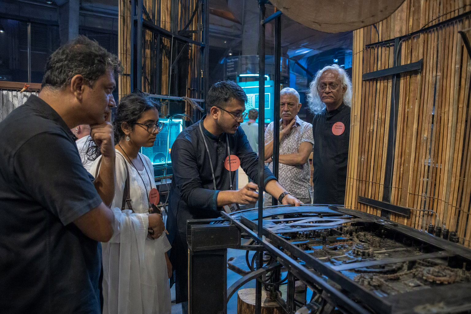Members gathering around a cyan-lit astronomy prototype during a behind-the-scenes preview