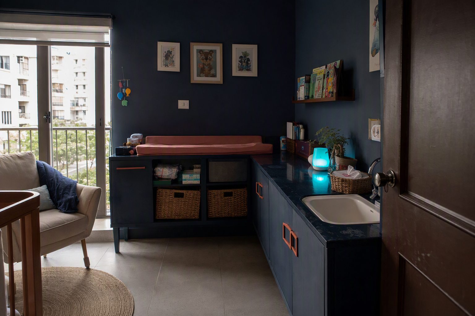 A private family care room with an adjustable changing bench, sink, chair, and child-height hooks